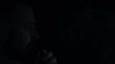 Elektronik sigara içen vahşi sakallı bir adamın yüzü. Esrarengiz, karanlık bir geçmişi olan, az dumanlı bir adam..