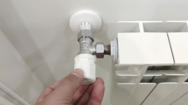 Bir erkeğin eli odadaki radyatörleri düzenler. Isı ve soğuk için termostat. Kontrollü ısıtma, yakın çekim..