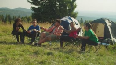 Neşeli çoklu etnik çeşitlilikte gezginler sabahları kamp alanında canlandırıcı kahve içerler.