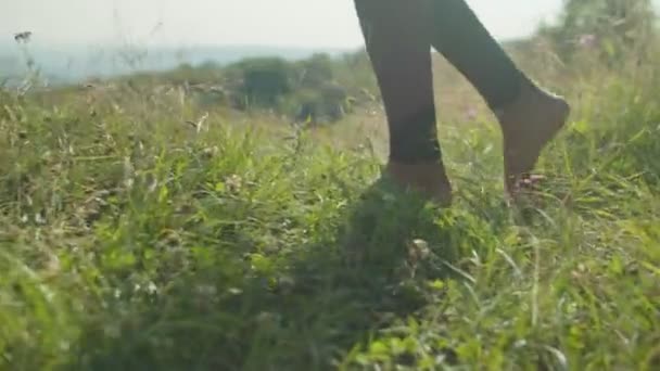 Κοντινό πλάνο του λεπτού ξυπόλυτη γυναικεία πόδια περπάτημα σε μαλακό γρασίδι το καλοκαίρι στα βουνά κατά την ανατολή — Αρχείο Βίντεο