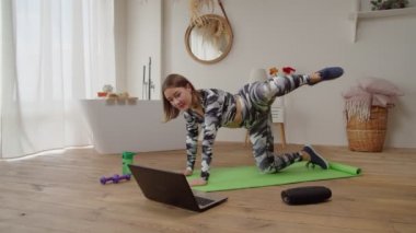 Çevrimiçi yoga kursunda spor yapan aktif bir kadın. Kapalı alanda deniz kabuğu egzersizi yapıyor.