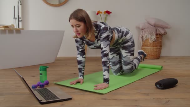 Jolie motivation sportive fitness femme pratiquant le yoga en ligne classe avec ordinateur portable dans la chambre domestique — Video