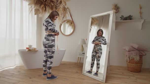 Happy sporty fit vrouw meten taille met tape meten na gewichtsverlies thuis — Stockvideo