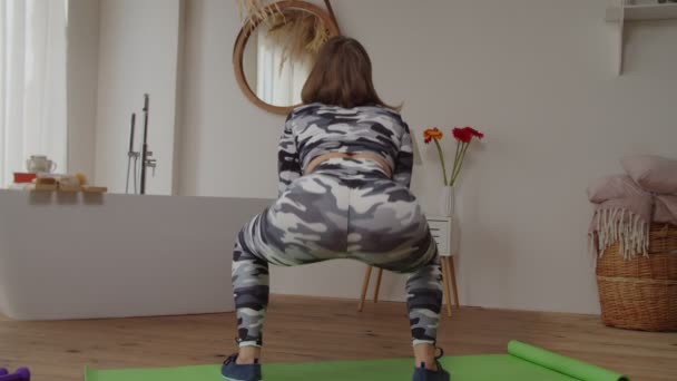 Milieu de fitness sportif actif squatting féminin tout en faisant de l'exercice dans la salle domestique — Video
