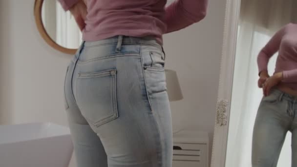 Close-up gefrustreerde vrouw proberen te ritsen strak jeans in de voorkant van de spiegel na het winnen van gewicht — Stockvideo