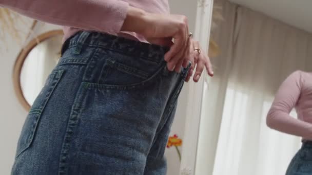 Nahaufnahme weiblicher Hände, die den Erfolg des Gewichtsreduktionsprogramms durch das Tragen alter Jeans zeigen — Stockvideo
