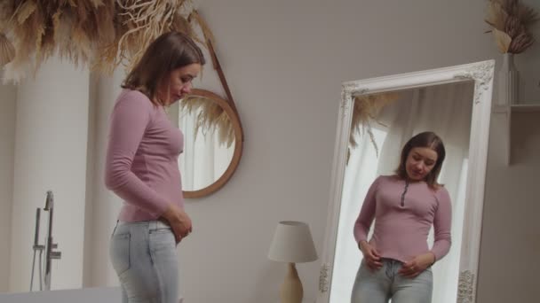 Feldúlt, kedves felnőtt nő elégedetlen a tükörben való megjelenésével, miután felszedett pár kilót. — Stock videók