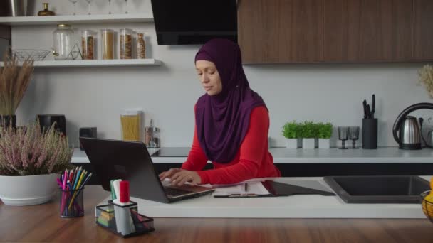 Lovely ανεξάρτητη μουσουλμάνα γυναίκα σε hijab δικτύωση σε απευθείας σύνδεση στο φορητό υπολογιστή στο σπίτι — Αρχείο Βίντεο