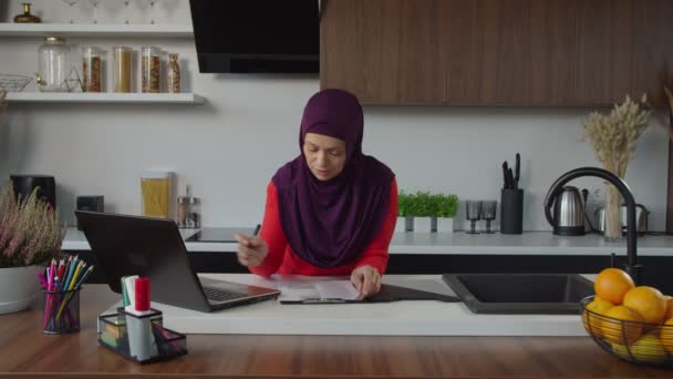 Ganska modern arabisk hijab affärskvinna som arbetar på laptop pc i hushållskök — Stockvideo