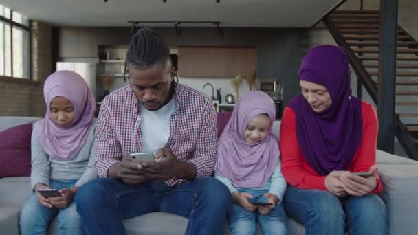 Positiv vielfältige multirassische muslimische Familie mit kleinen Mädchen, die im Haus online auf Smartphones surfen — Stockvideo