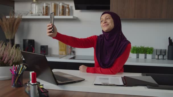 Alegre atractivo Oriente Medio hembra en hijab posando para selfie disparo en el teléfono celular en el interior — Vídeos de Stock