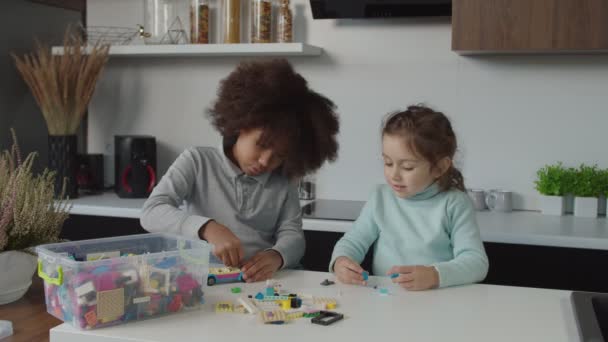 Creative adorable multicultural little girls playing with toy constructor blocks indoors — Stock Video