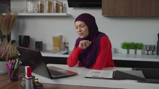 Χαρούμενη γοητευτική γυναίκα arab hijab κάνει βιντεοκλήση σε απευθείας σύνδεση χρησιμοποιώντας το φορητό υπολογιστή σε εσωτερικούς χώρους — Αρχείο Βίντεο