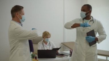 Afro-Amerikan doktor ve yüz maskeli meslektaşı hastanede dirsek teması yapıyor.