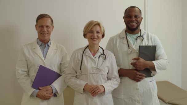 Retrato de amistoso y diverso equipo médico multiétnico sonriendo en el consultorio médico — Vídeos de Stock