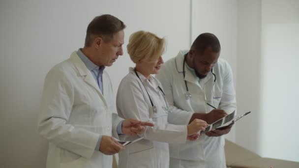 Група професійних багатоетнічних медичних колег, які переглядають результати ультразвукового сканування в приміщенні — стокове відео