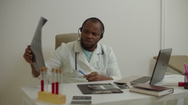 Czarny mężczyzna lekarz wideokonferencje online, konsultacje z kolegą na temat diagnozy pacjenta — Wideo stockowe
