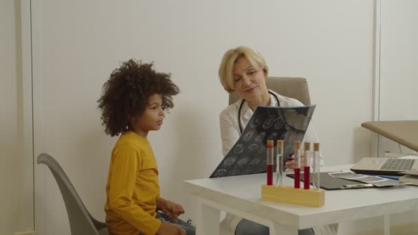 Schattig Afrikaans Amerikaans jongetje op bezoek bij mooie vrouwelijke huisarts in medische kliniek — Stockvideo