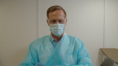 PPE 'deki erkek sağlık görevlisi hastanede koronavirüs için PCR testi için hasta numunesi alıyor.