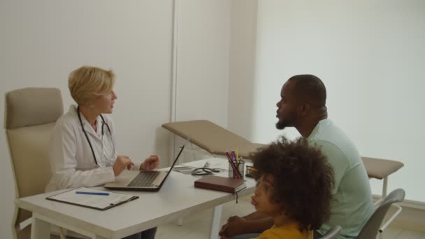 Cuidando do pai afro-americano com o filho pequeno doente recebendo consulta médica pelo pediatra — Vídeo de Stock
