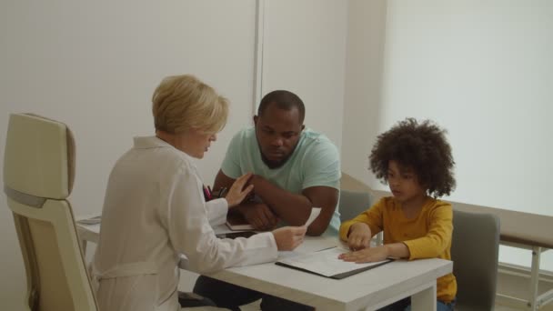 Empathische vrouwelijke arts vertelt slecht nieuws aan zwarte vader overstuur over ziekte van kleine zoon in kliniek — Stockvideo