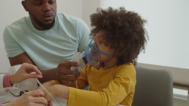 Malade âge élémentaire garçon noir portant un nébuliseur masque, inhalant des médicaments de vapeur à l'hôpital — Video