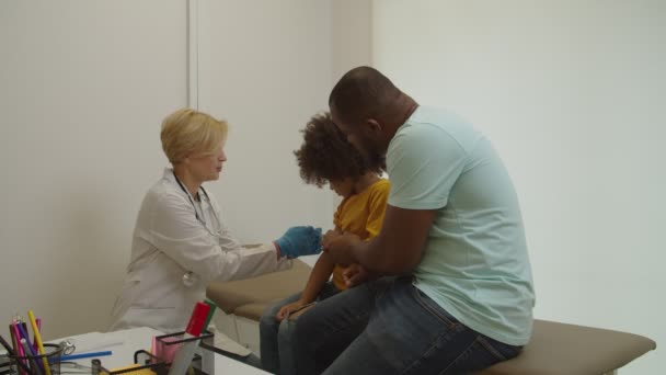 Fürsorglicher Allgemeinmediziner gibt kleinem afrikanischen Kind im Krankenhaus intramuskuläre Injektion in Arm