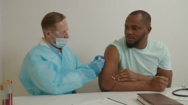 Pen 'deki erkek doktor, hastanede koronavirüs enfeksiyonu için Afrikalı Amerikalı bir adama aşı yapıyor.