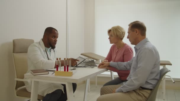 Afrikaans-Amerikaanse arts het schrijven van digitale recept op tablet pc naar middelbare leeftijd mannelijke patiënt — Stockvideo