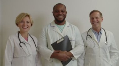 Çeşitli etnik çeşitlilikteki tıp arkadaşlarının portresi hastanede dostane bir gülümsemeyle bakıyorlar.