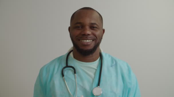 Portræt af munter positiv afrikansk amerikansk mand læge i lab coat smilende på hospitalet – Stock-video