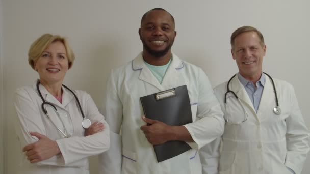 Sonriendo confiado y diverso equipo médico multicultural posando con los brazos cruzados en el hospital — Vídeos de Stock