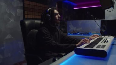 Yeni parça üzerinde çalışan yaratıcı stil sahibi müzisyen ses kayıt stüdyosunda synthesizer çalıyor.
