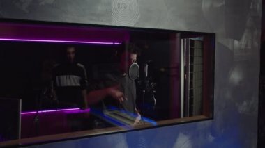 Havalı Afro-Amerikan hip-hop sanatçılarından ilham alarak mikrofona şarkı söylüyor, müzik stüdyosunda şarkı kaydediyor.