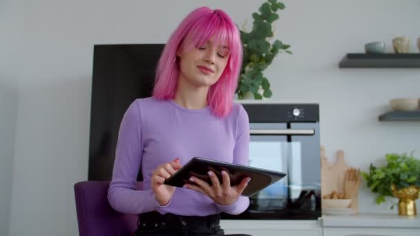 Elegante mujer bonita con red de pelo rosa en línea en la tableta digital en casa — Vídeos de Stock