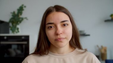 Çekici, genç, esmer bir kadının mütevazı gülümsemesiyle yakın plan portresi.
