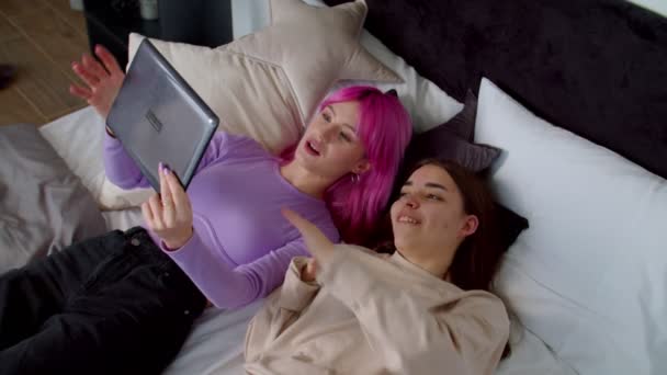 Pretty woman with physical disability and girlfriend sharing tablet pc in bed — Stock Video