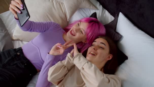 Беззаботная женщина и подруга с врожденной аномалией делают селфи в постели — стоковое видео