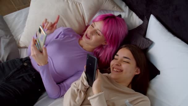 快乐迷人的女性朋友，带着智能手机，享受床上的闲暇 — 图库视频影像