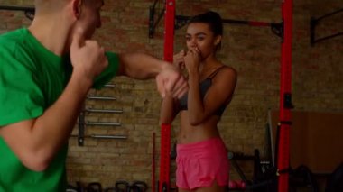 Erkek boks koçu Afrikalı Amerikalı kadın dövüşçüye kanca yumruğu öğretiyor.