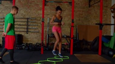 Sportif formda Afro-Amerikan kadın çeviklik merdiveni talimi yapıyor.