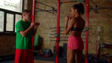 Erkek boks antrenörü spor salonunda Afrikalı kadın boksöre kayma tekniği gösteriyor.