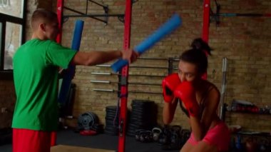 Azimli atletik siyah kadın boksör antrenörle kombinasyon çalışması yapıyor.