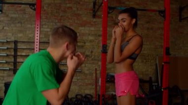 Erkek boks eğitmeni Afrikalı güzel kadın dövüşçüye boks taktikleri öğretiyor.