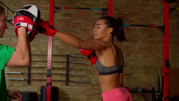 Motiverad atletisk svart kvinnlig boxare slående fokus handske under träning på gym — Stockvideo