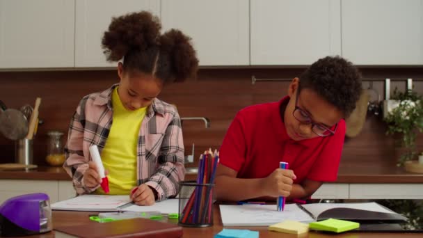 Cute cheerful elementary age African American siblings drawing pictures at home — Wideo stockowe