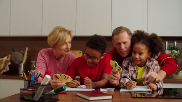 Pečující prarodiče učí abecedu rozkošným mnohonásobným dětem v interiéru — Stock video