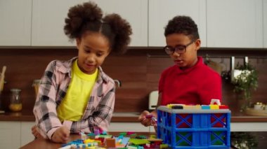 Yaratıcı ergenlik öncesi siyah çocuklar renkli oyuncak bloklarıyla inşa ediyorlar.
