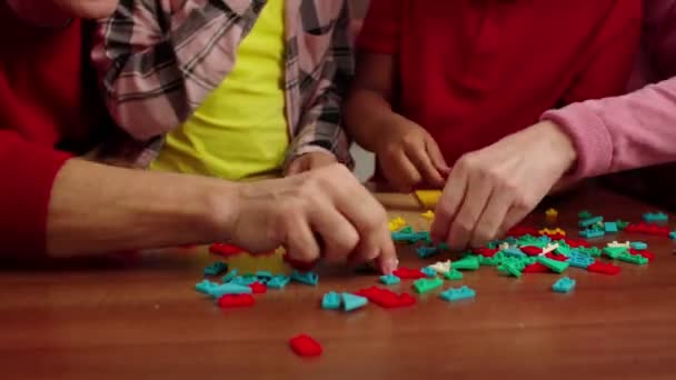 Close-up de mãos humanas escolhendo peças de quebra-cabeça de classificação coloridas — Vídeo de Stock