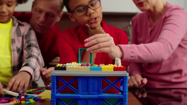 Close-up van multiraciale broers en zussen en grootouders die met speelgoedconstructeur spelen — Stockvideo